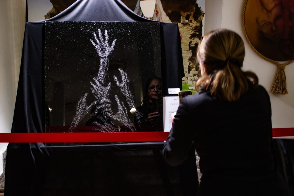 Farkhunda — hands reaching upward in fractured glass, at the Aydın exhibition