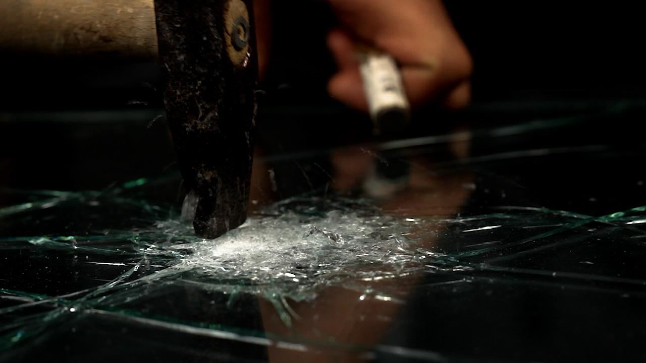 A hammer striking laminated glass in the studio