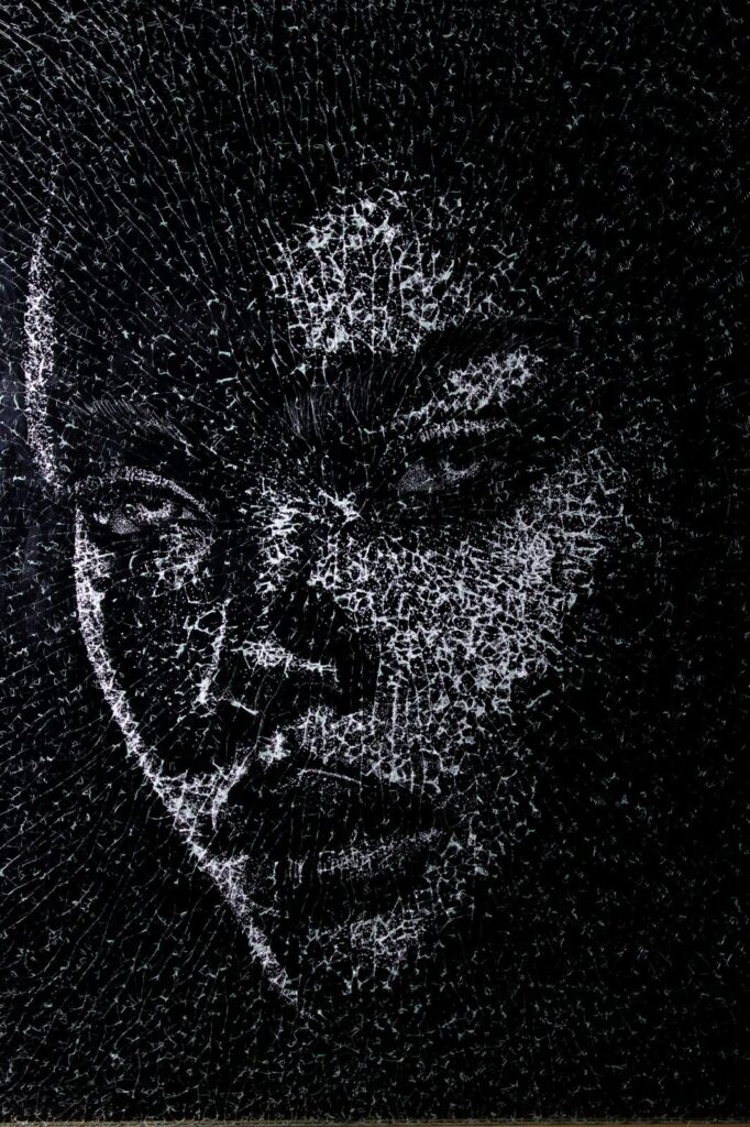 Sadie — a woman’s face drawn in white fractures on black-backed glass