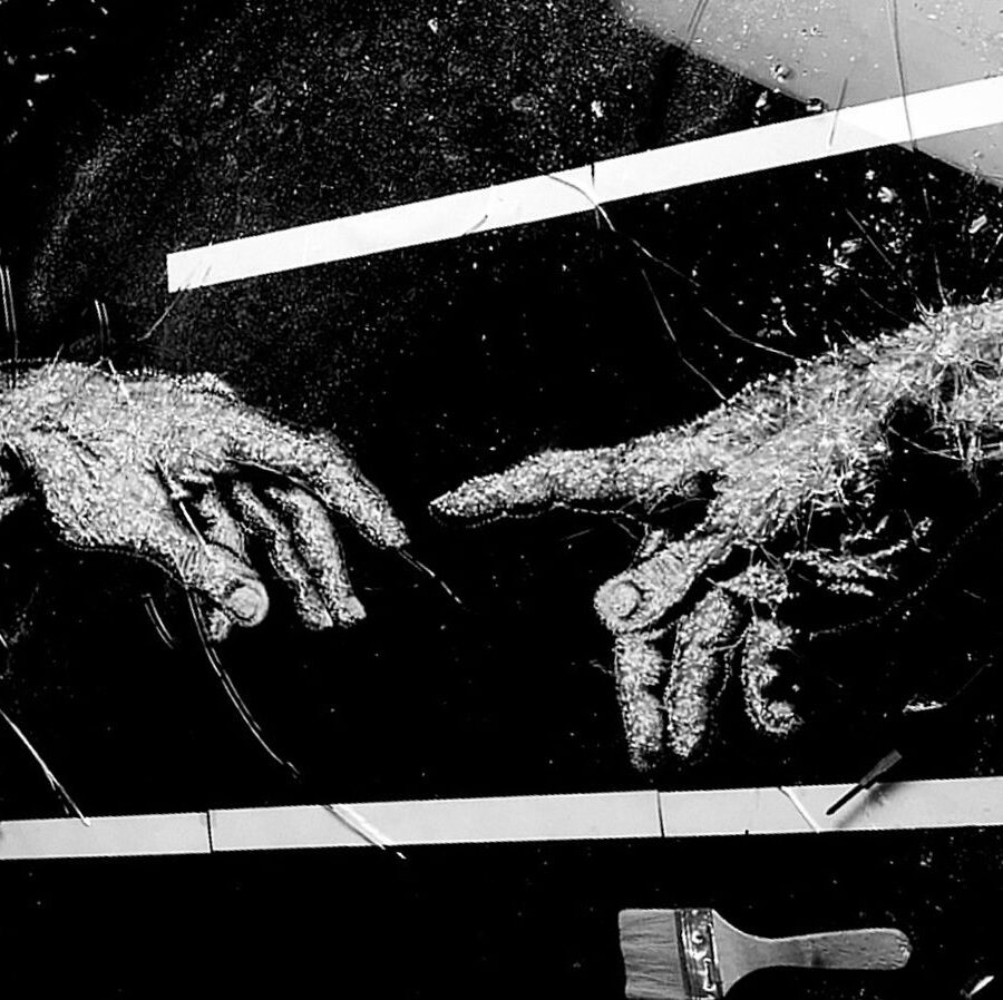 The Creation of Adam — two reaching hands formed by fractures in glass